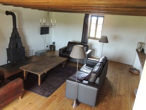A cozy living room with a fireplace, sofa, table, and lamp. - Cottage 'Gîte Grand-mère' with Private Pool, Terrace, and Wi-Fi (Charron)