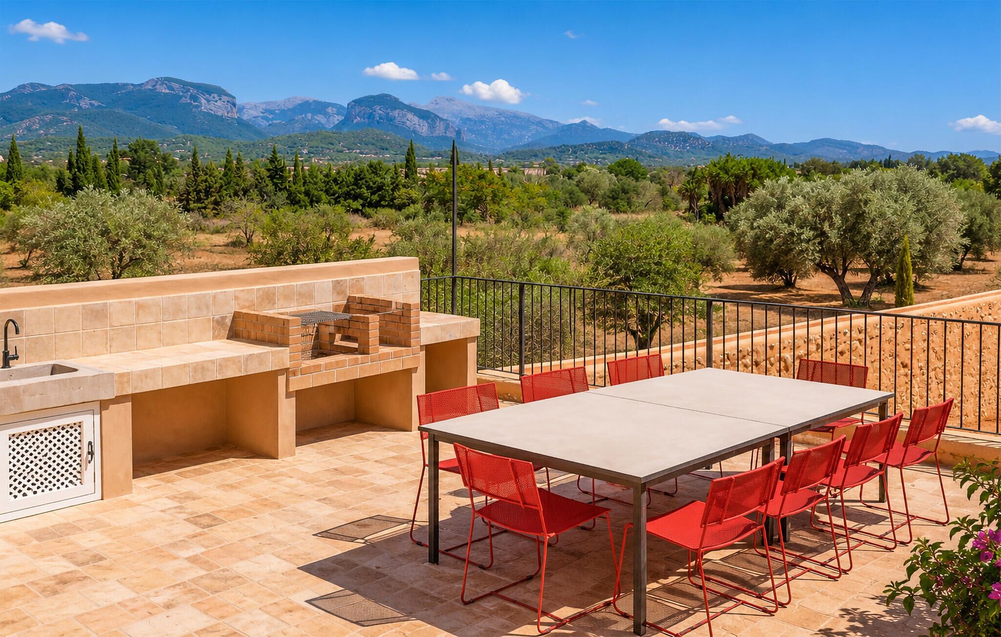 Eine Terrasse im Freien mit Grillplatz, einem Tisch und Stühlen sowie Blick auf Berge.
