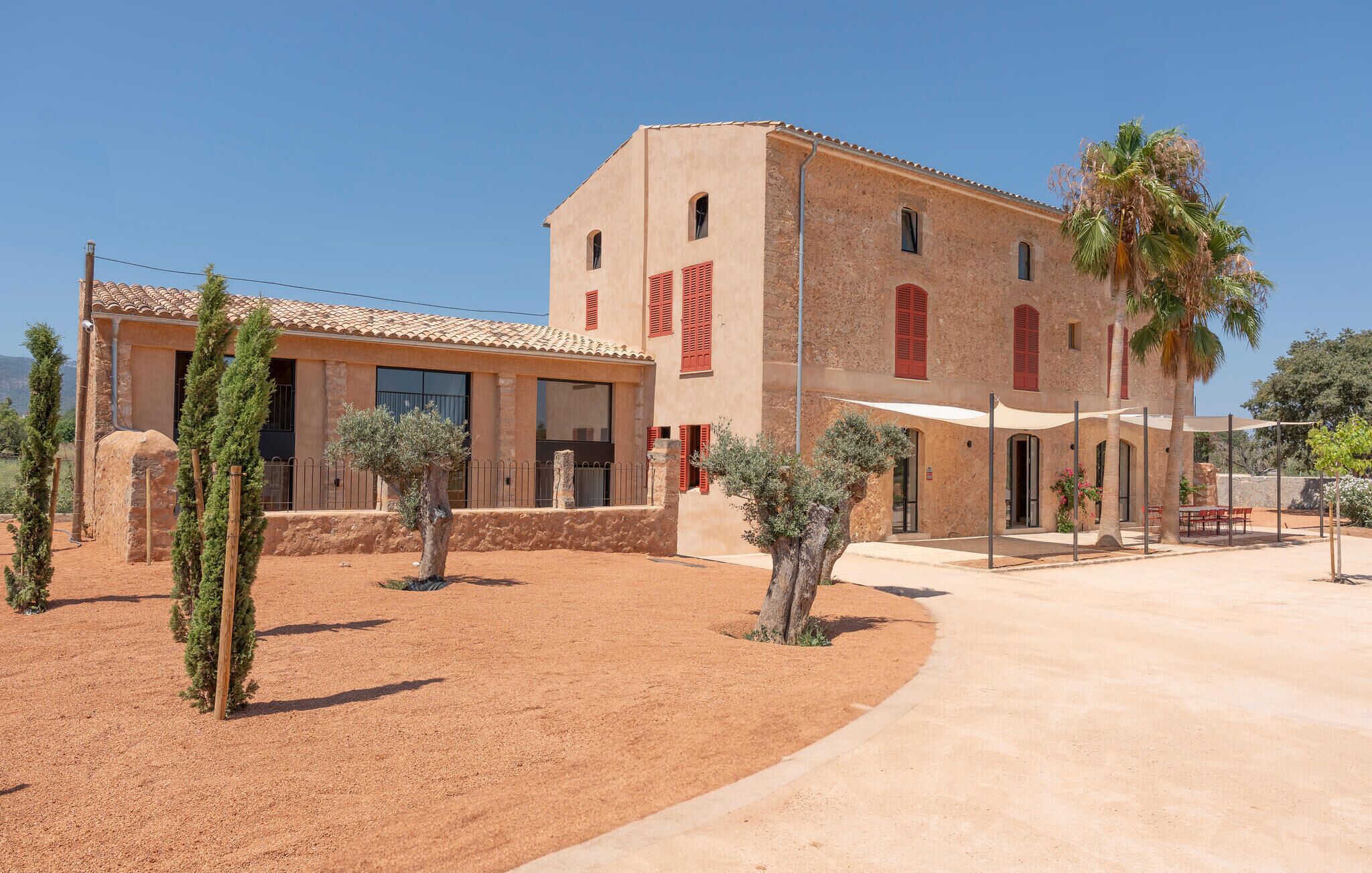 A building with a courtyard, featuring a mix of architectural styles, including a traditional facade with red shutters and a modern section with large windows.