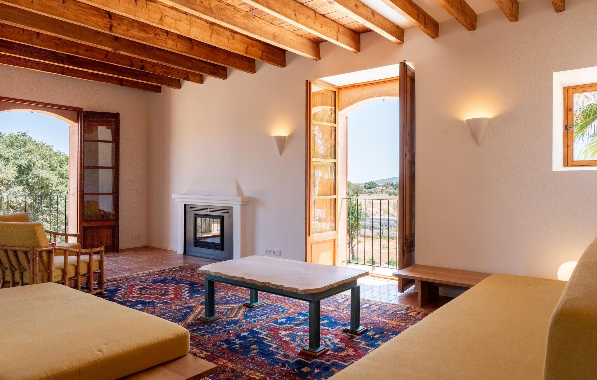 Une pièce avec une cheminée, un balcon et une vue sur l’extérieur.