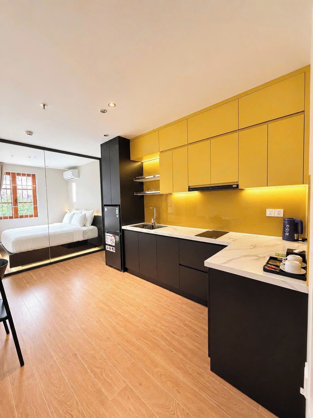 Quarto de hotel moderno com cozinha, uma cama e vista para o exterior.