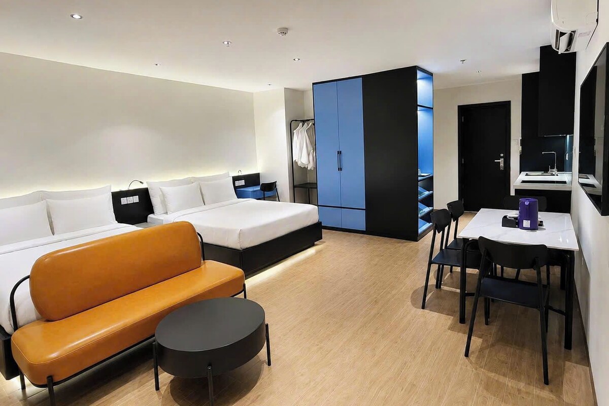 Quarto de hotel moderno com cama, sofá, mesa de jantar e guarda-roupa.