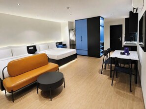 Quarto de hotel moderno com cama, sofá, mesa de jantar e guarda-roupa.