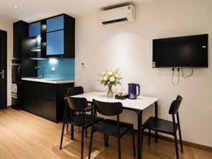 Cozinha moderna com fogão embutido, painel de azulejos azul e televisão de tela plana na parede.