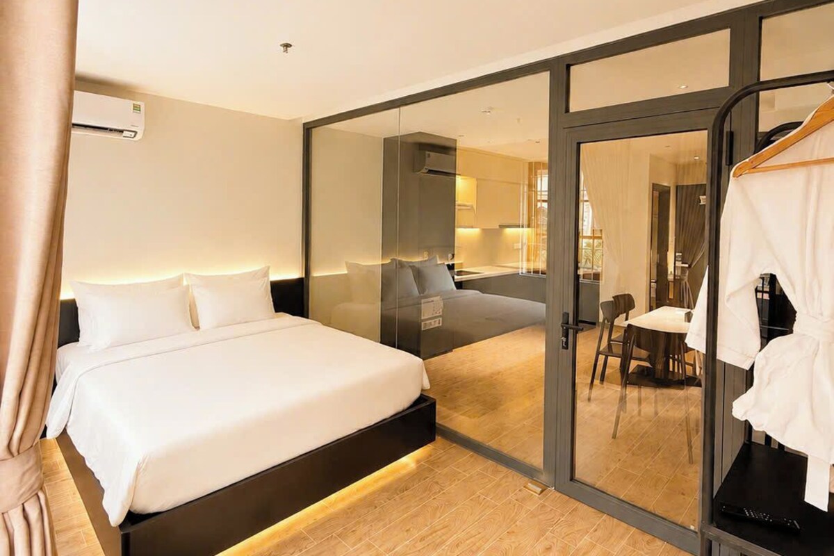 Quarto de hotel moderno com uma cama grande, divisória de vidro e vista para a área de refeições.