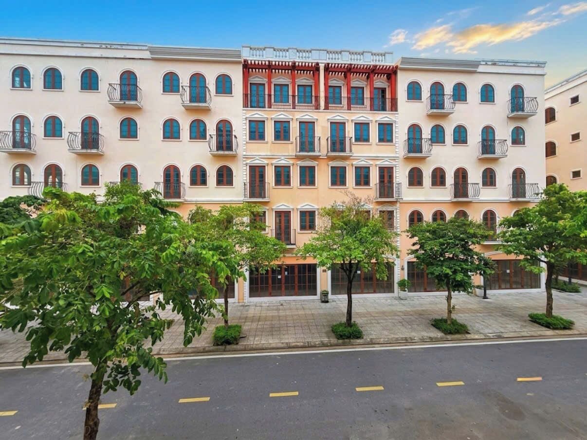 Un hotel de varios pisos con fachada simétrica, balcones y una entrada central.