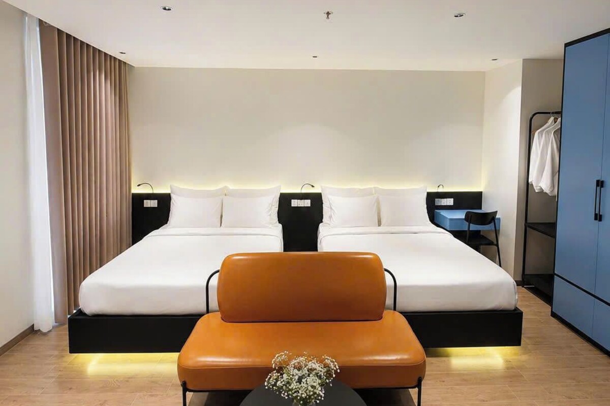 Een moderne hotelkamer met een groot bed, een bank, een kleintje tafeltje met een vaas en een kledingkast.
