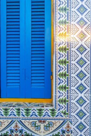 Una puerta azul con listones horizontales, ubicada en una pared de baldosas estampadas.