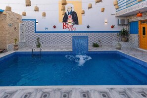 A swimming pool with a mural, a blue door, and a patterned wall.