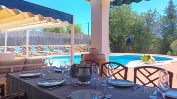 An outdoor dining area with a pool, lounge chairs, and a covered seating area.