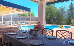 Un espace extérieur aménagé pour les repas, avec une piscine, des chaises longues et un coin salon abrité.