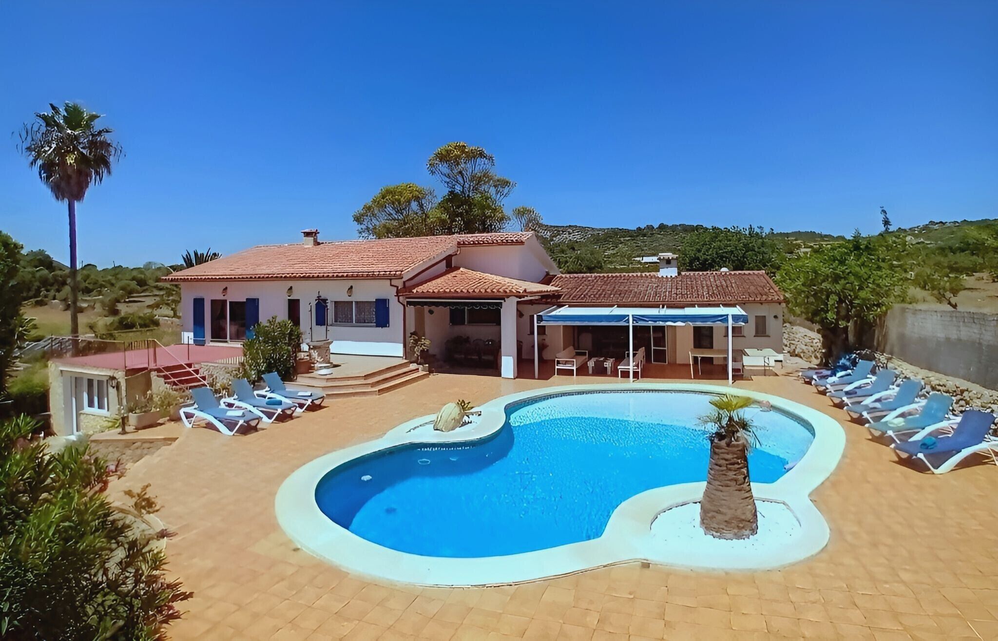 Ein zweistöckiges Haus mit Swimmingpool, Liegestühlen und einer überdachten Terrasse.