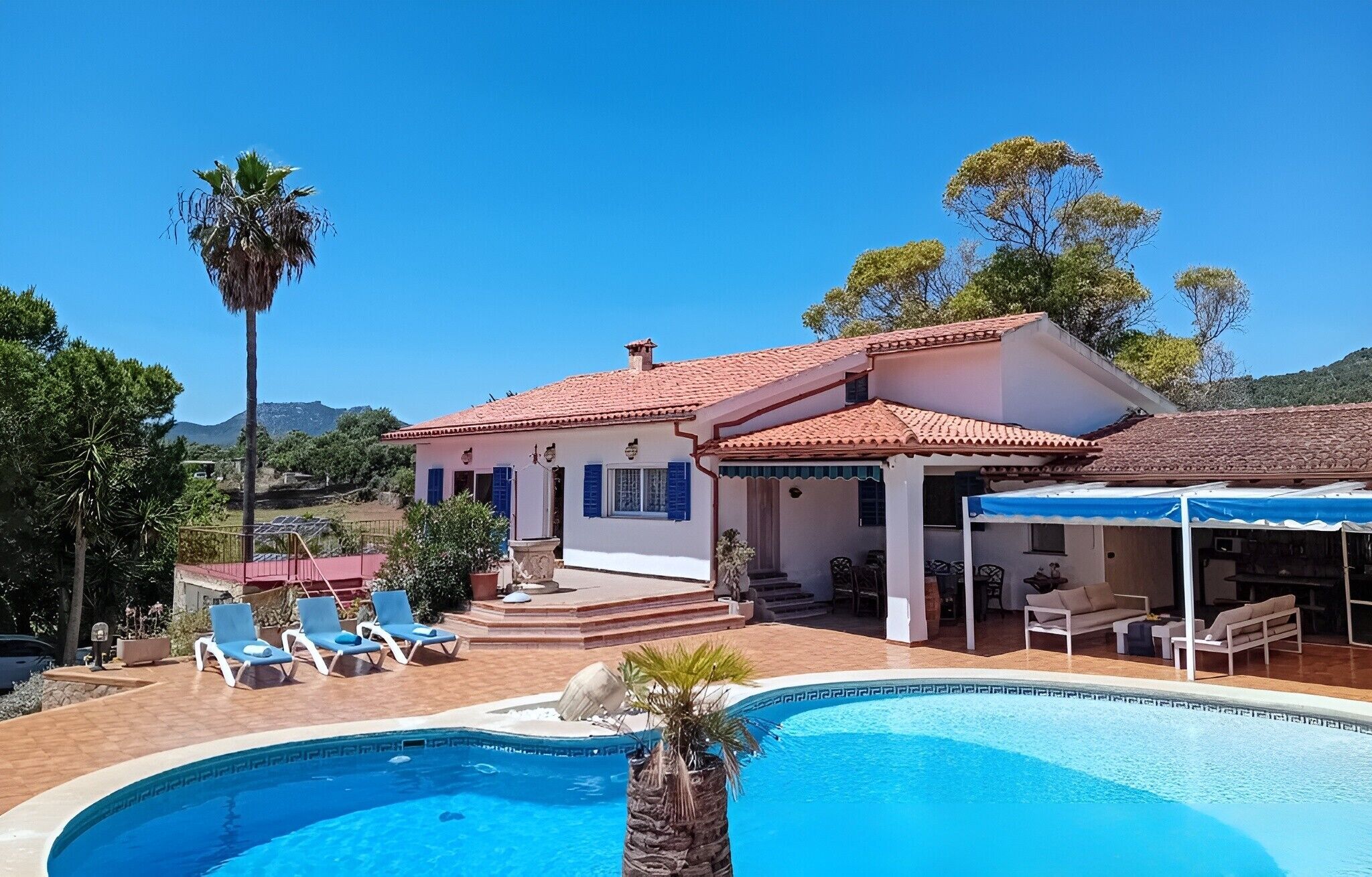 A two-story house with a swimming pool, outdoor seating, and a covered patio.