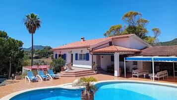 A two-story house with a swimming pool, outdoor seating, and a covered patio.