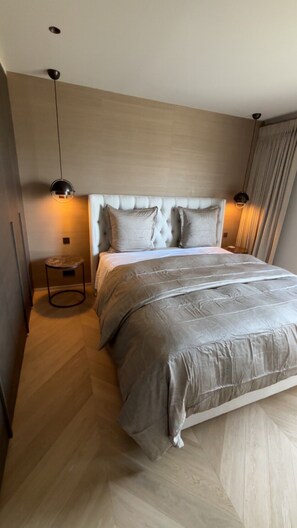 A modern bedroom with a tufted headboard, a round bedside table, and a large bed with a grey duvet. - Luxury Apartment in Nice – Sea and Mountain Views, Near Monaco (Nice)