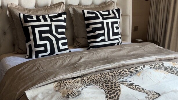 A bed with a patterned bedspread, two pillows with a geometric design, and a headboard. - Luxury Apartment in Nice – Sea and Mountain Views, Near Monaco (Nice)
