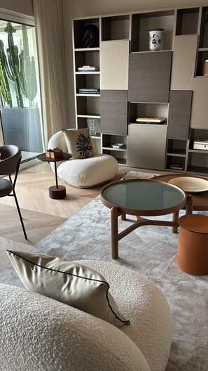 A modern living room with a sectional sofa, a round coffee table, and a built-in bookshelf. - Luxury Apartment in Nice – Sea and Mountain Views, Near Monaco (Nice)