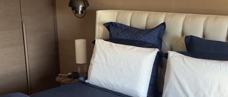 Una habitación de hotel con una cama, una mesita de noche, una lámpara y un armario.