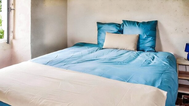 A bed with a blue and white duvet, a beige pillow, and a wooden nightstand with a lamp. - Gorgeous home in Channay-Sur-Lathan with WiFi (Channay-Sur-Lathan)
