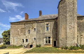 Un edificio histórico de piedra con múltiples ventanas, una entrada central y una torre alta.