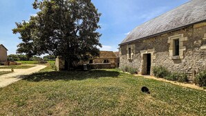 A stone building with a large tree in front, a dirt path, and a grassy area. - Gorgeous home in Channay-Sur-Lathan with WiFi (Channay-Sur-Lathan)