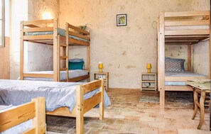 Una habitación con literas, una mesita pequeña y un estante en la pared.