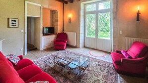 A living room with a television, red chairs, a glass coffee table, and a large window with a view of greenery. - Gorgeous home in Channay-Sur-Lathan with WiFi (Channay-Sur-Lathan)