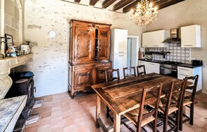 Eine rustikale Küche mit Holztisch und -stühlen, einem eingebauten Schrank und einer Deckenleuchte.