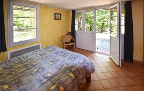 Ein Schlafzimmer mit Bett, einem Sessel, einem Fenster und einer Schiebetür zu einem Außenbereich.