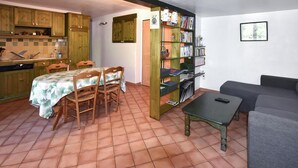 Un espace de vie compact comprenant un coin repas, une kitchenette et une bibliothèque.