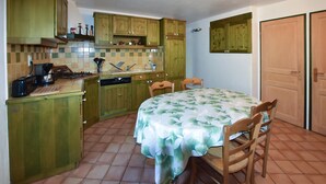 Une cuisine de taille réduite avec des meubles en bois, une table à manger avec des chaises et un sol carrelé.
