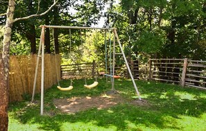A swing set in a fenced outdoor area with trees and a wooden fence in the background. - Pet friendly home in Saint-Ambroix with WiFi (Saint-Ambroix)