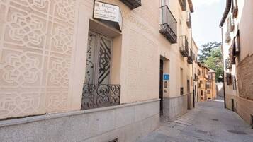 Una calle estrecha con un edificio que presenta intrincados diseños en la fachada, una puerta visible y un letrero de estacionamiento azul.