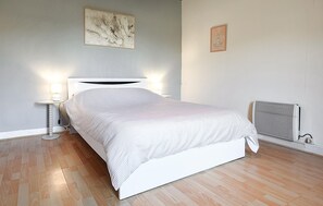 A neatly made bed with a white headboard, a bedside lamp, and a radiator on the wall.