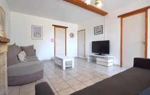 Un salon comprenant un canapé, un téléviseur, une table basse et une table à manger.