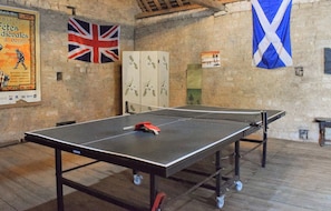 Ein Tischtennistisch in einem Raum mit Steinwänden, einer britischen Flagge und einer schottischen Flagge.