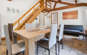 Ein Essbereich mit einem Holztisch, Stühlen, einer Treppe und einem Sofa.