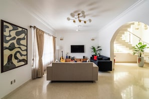 Ein modernes Wohnzimmer mit einer Couch, einem Flachbildfernseher und einer Treppe, die in eine obere Ebene führt.