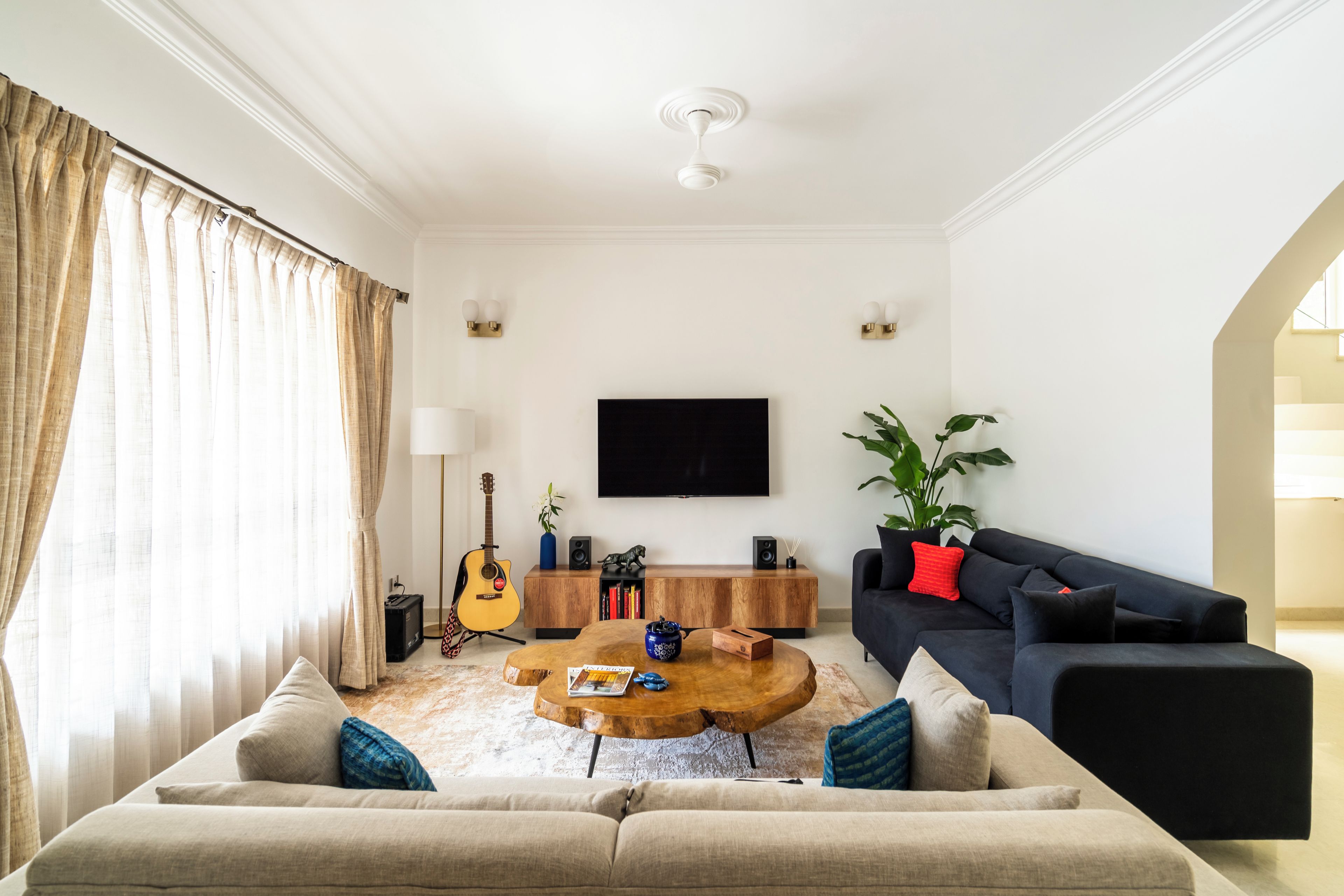 A living room with a sofa, coffee table, TV, and a guitar.