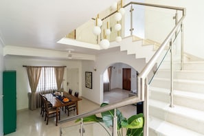 A modern interior with a dining area, staircase, and a view of the living space.