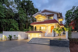 A two-story house with a red-tiled roof, a balcony, and a staircase leading to the entrance. - Staymaster Caetano-3BR Villa with Pool  (Siolim)