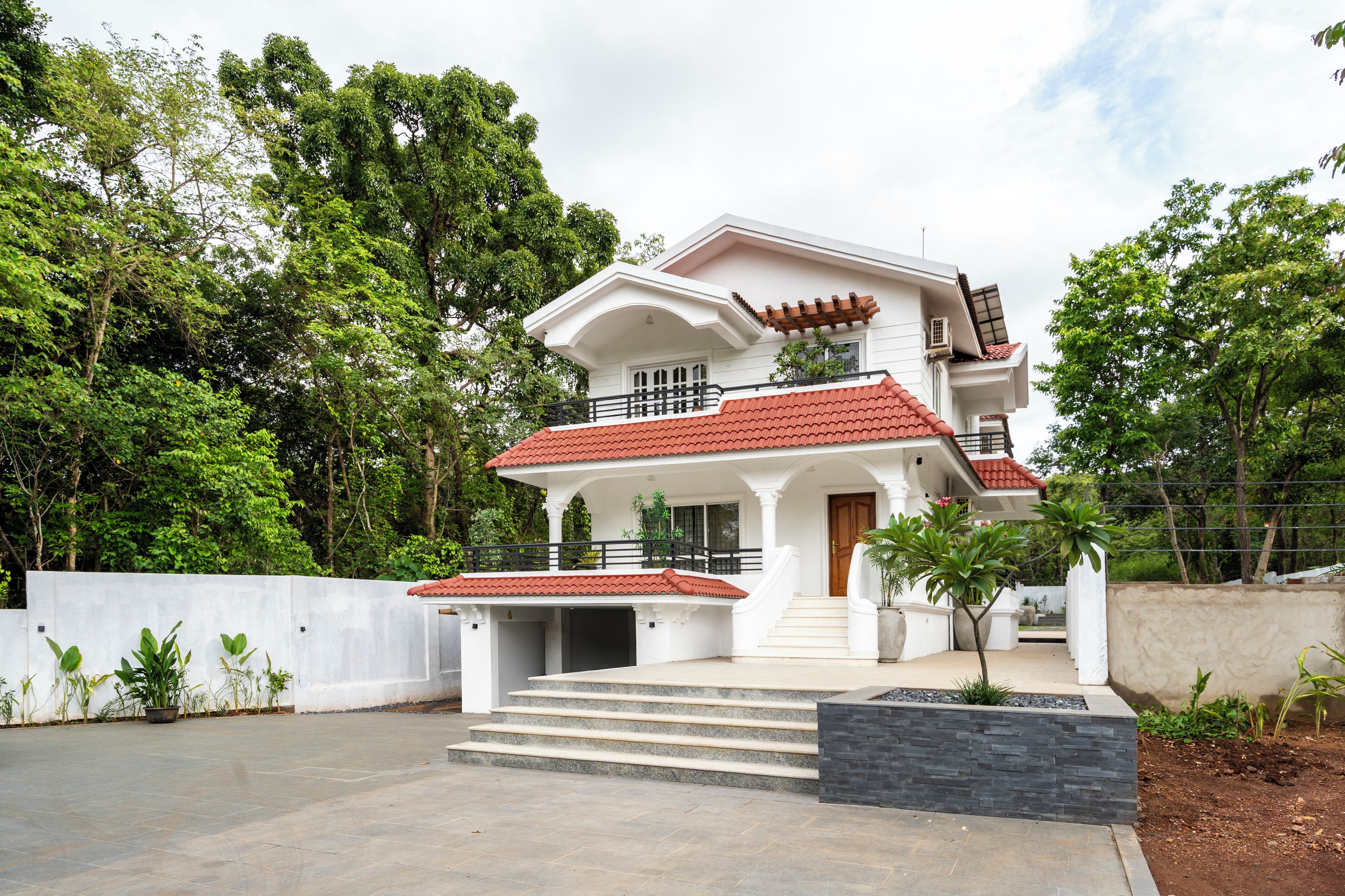 A two-story house with a red-tiled roof, a front porch, and a staircase leading to the entrance.
