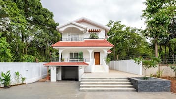 A two-story house with a red-tiled roof, a front porch, and a staircase leading to the entrance.