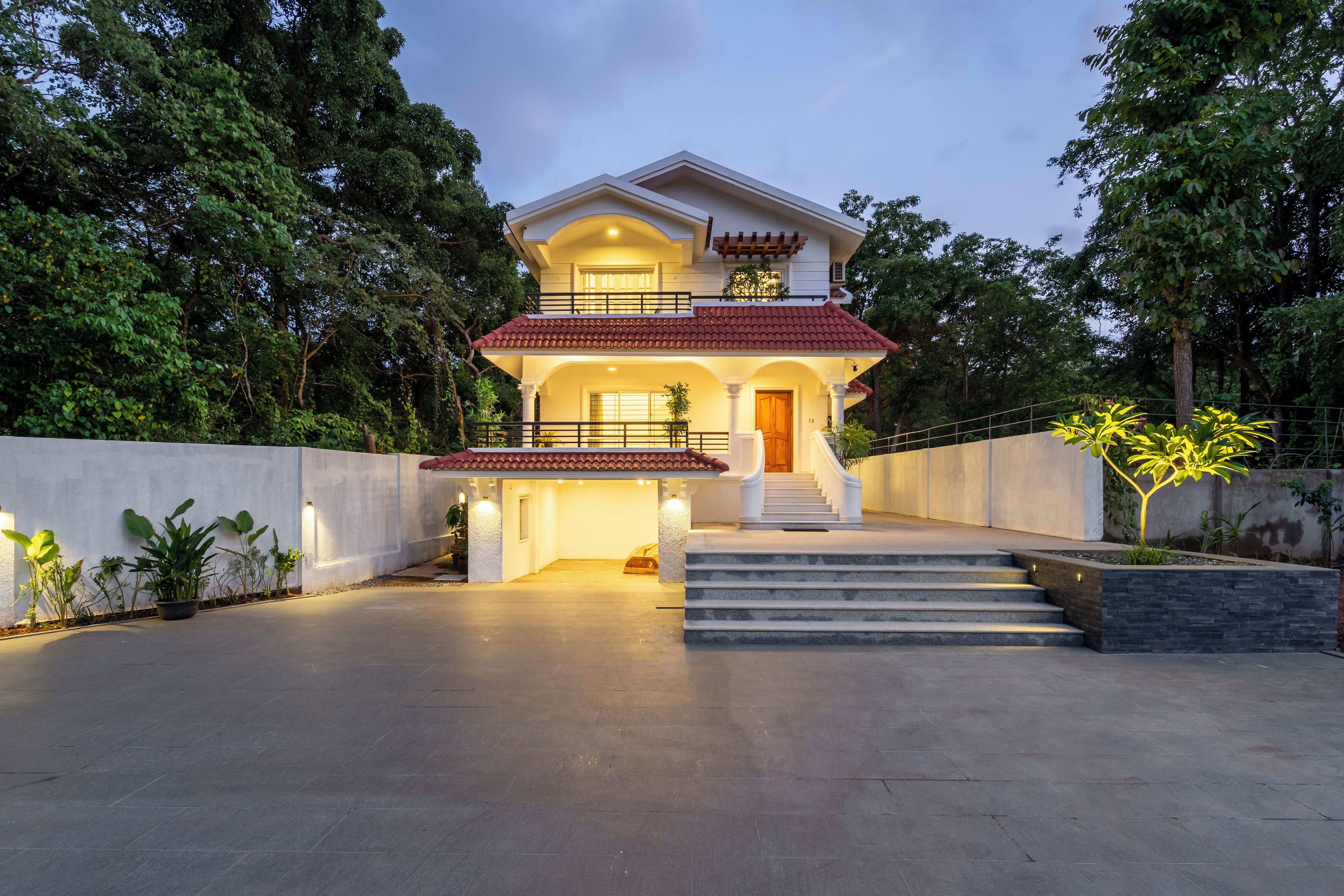 A two-story house with a balcony, a staircase leading to the entrance, and a driveway.