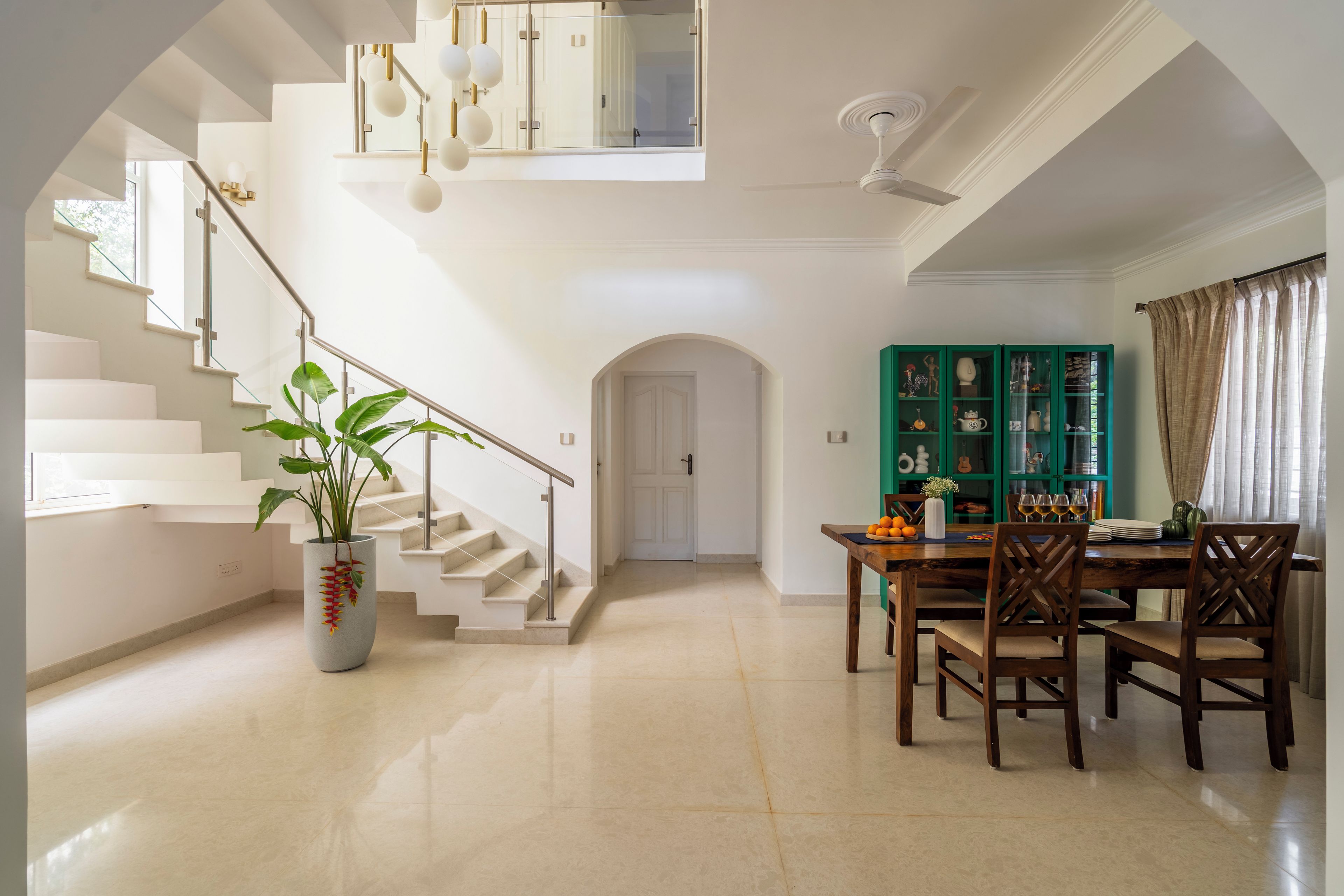 A spacious interior with a staircase, a dining area, and a green cabinet with decorative items.