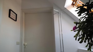 Una habitación con una puerta, un interruptor de luz y un perchero metálico.