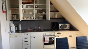 Una cocina compacta con microondas, cafetera y lavabo.