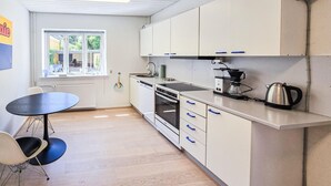 Una cucina compatta con mobili bianchi, un piano di lavoro nero e una macchina da caffè.