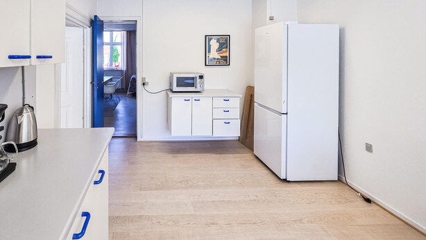 Una cucina piccola con mobili bianchi, un forno a microonde e un frigorifero.