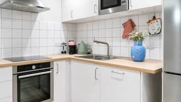 A modern kitchen with white cabinetry, stainless steel appliances, and a wooden countertop.